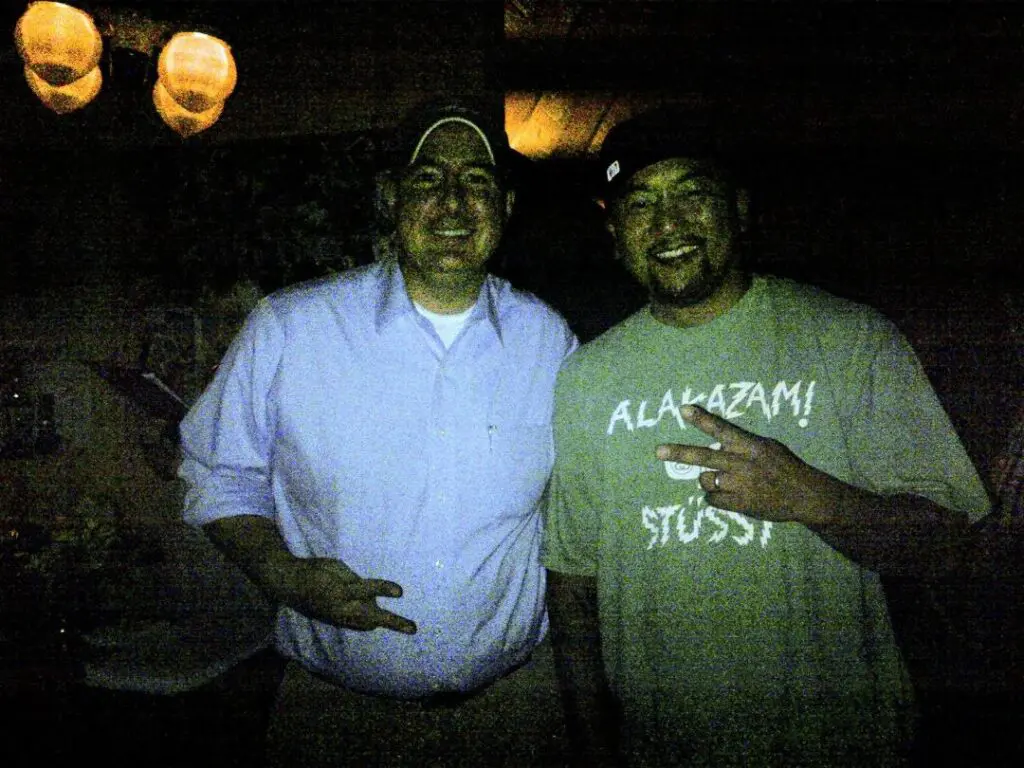 Two men standing next to each other in a dark room.