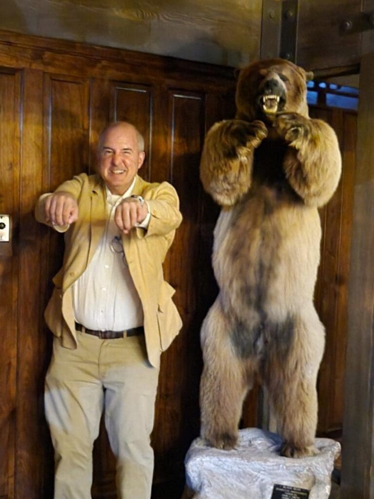 A man posing next to a bear statue.