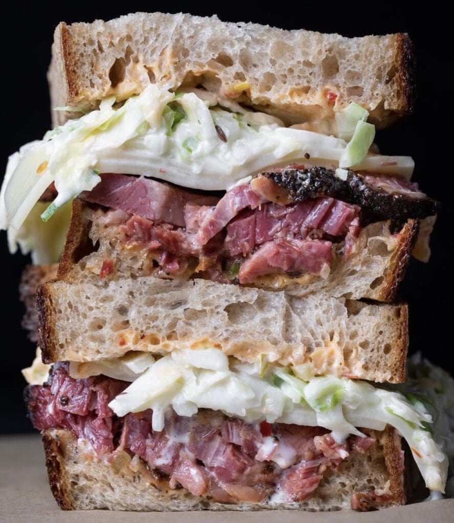 Stacked sandwich with meat and coleslaw filling.