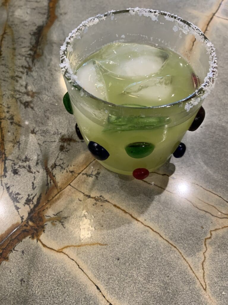 Decorative glass with iced green beverage.