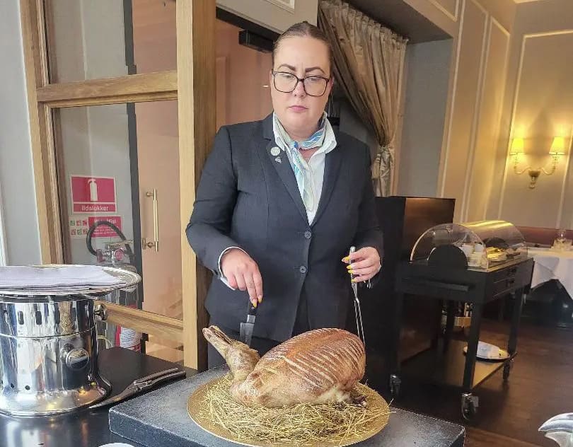 Woman in suit carving roasted duck.