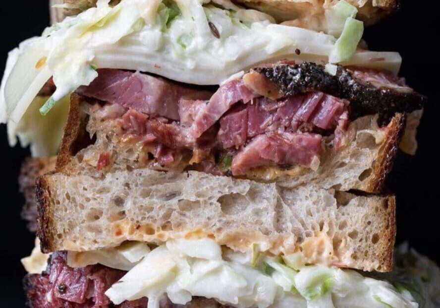 Stacked sandwich with meat and coleslaw filling.