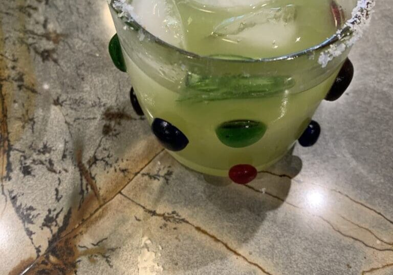 Decorative glass with iced green beverage.